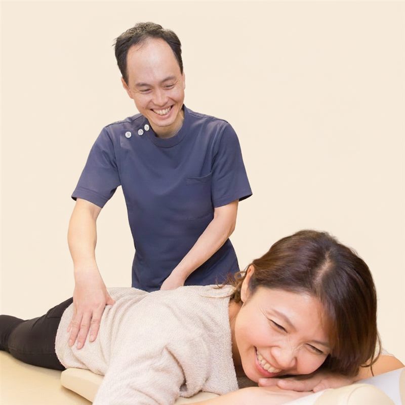 笑顔で施術を受ける女性患者と院長